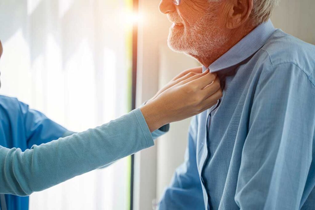A caregiver assists an older adult by organizing and dispensing medications at a shared table.