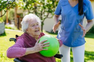 Older resident and family member talking at a table in a bright assisted living common room.